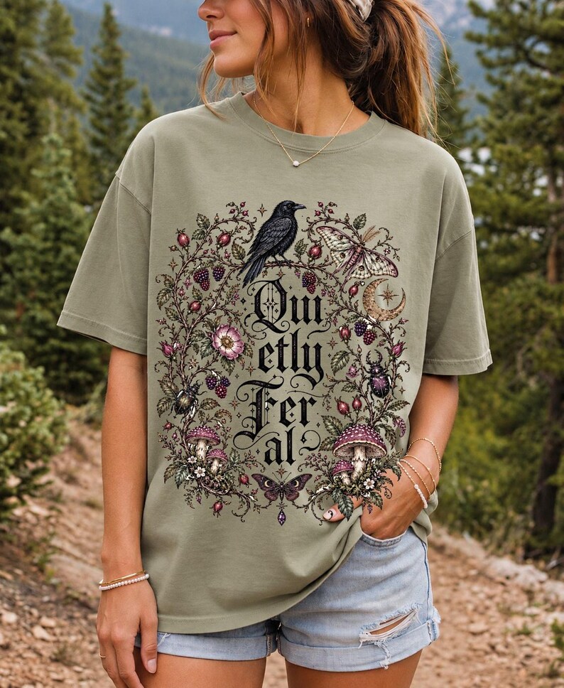 Raven on a wild rose branch with beetles and berries around blackletter text "Quietly Feral"