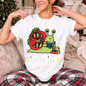 Cartoon snail reading a book with a bookshelf shell and the text One More Chapter