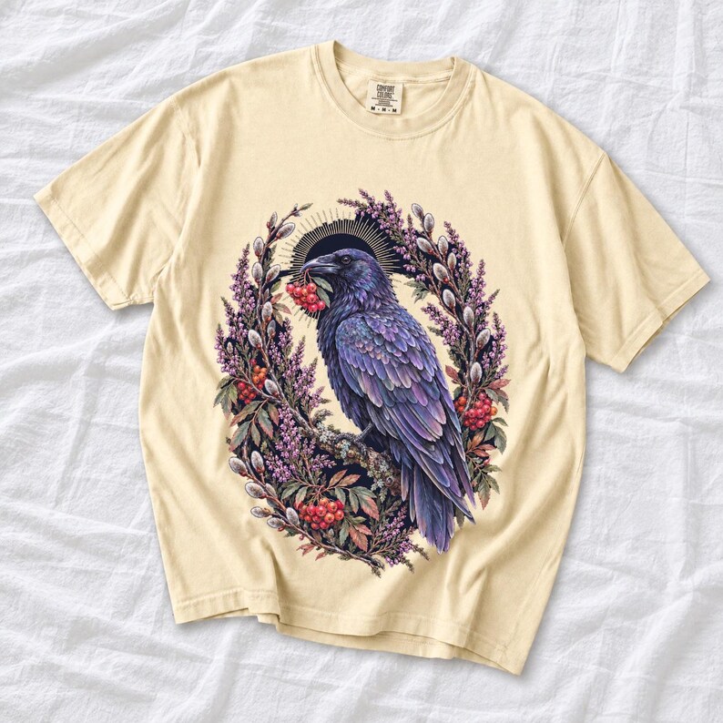 Raven holding a rowan berry inside an oval wreath of heather and catkins, painted cottagecore bird illustration