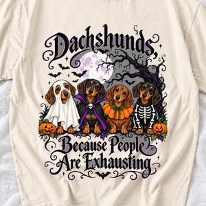 Four dachshunds in Halloween costumes under a spooky tree with text Dachshunds, Because People Are Exhausting