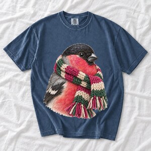Colored-pencil bullfinch bird wrapped in a chunky striped knit scarf, cozy winter birdwatcher t-shirt art