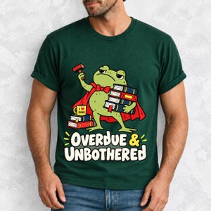 Grumpy cartoon frog librarian holding a stamp and a stack of books with the text Overdue & Unbothered
