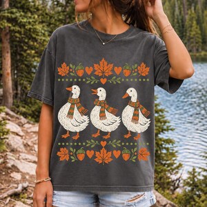 Three white ducks in striped scarves with acorn and maple leaf borders, retro screen print fall t-shirt art