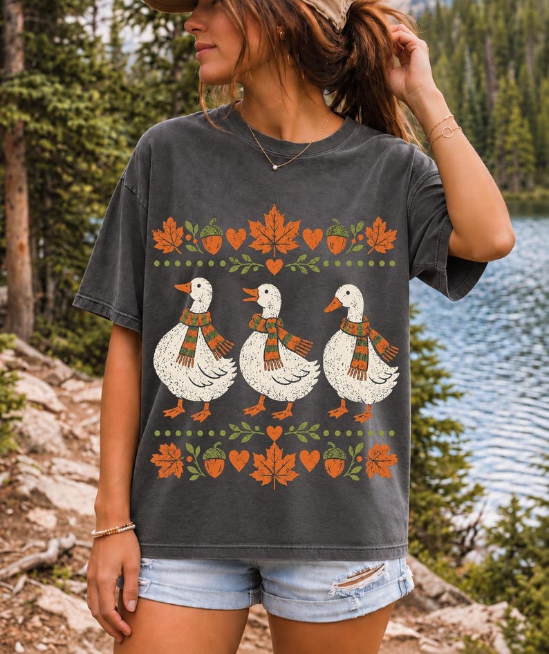 Three white ducks in striped scarves with acorn and maple leaf borders, retro screen print fall t-shirt art