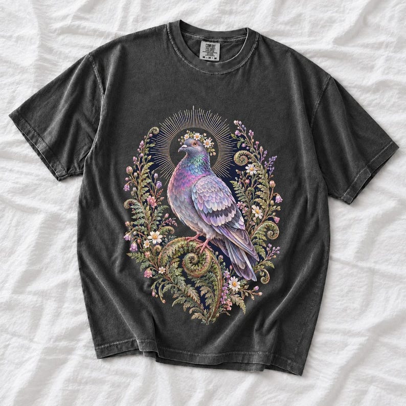 Painted pigeon wearing a daisy crown and glowing halo standing on a fern frond, whimsical cottagecore bird t-shirt art