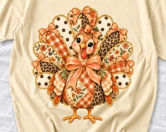 May include: A cream-colored t-shirt featuring a central graphic of a turkey. The turkey has a fan of tail feathers decorated with orange gingham, leopard print, polka dots, and floral patterns, accented with multiple orange bows.