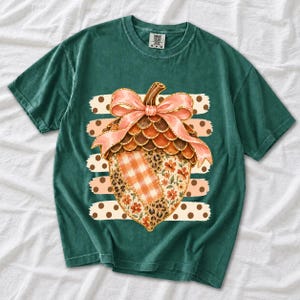 Giant patchwork acorn with a pink satin bow made of plaid, leopard and floral fabric on polka-dot stripes