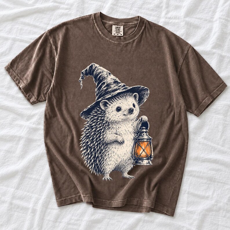 Etched pen illustration of a hedgehog in a witch hat holding a lantern, bone white with orange accent