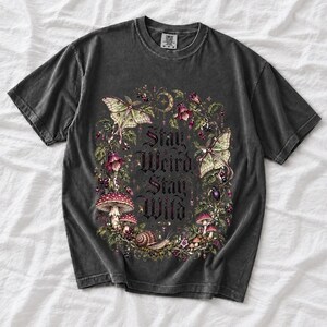 Victorian-style wreath of nightshade, luna moths and toadstools around the words "Stay Weird, Stay Wild"