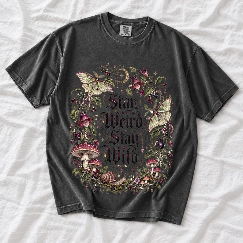 Victorian-style wreath of nightshade, luna moths and toadstools around the words "Stay Weird, Stay Wild"