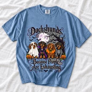 Four dachshunds in Halloween costumes under a spooky tree with text Dachshunds, Because People Are Exhausting
