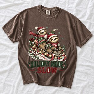 Two sloths in ugly sweaters riding a sled with lights and the text Holiday Mode: Slow
