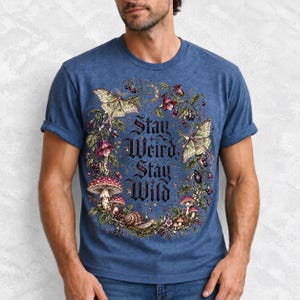 Victorian-style wreath of nightshade, luna moths and toadstools around the words "Stay Weird, Stay Wild"