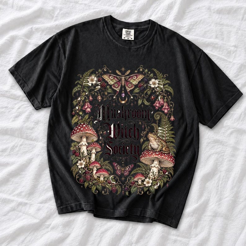 Blackletter text "Mushroom Witch Society" framed by fly agaric mushrooms, ferns and a toad on a mushroom cap