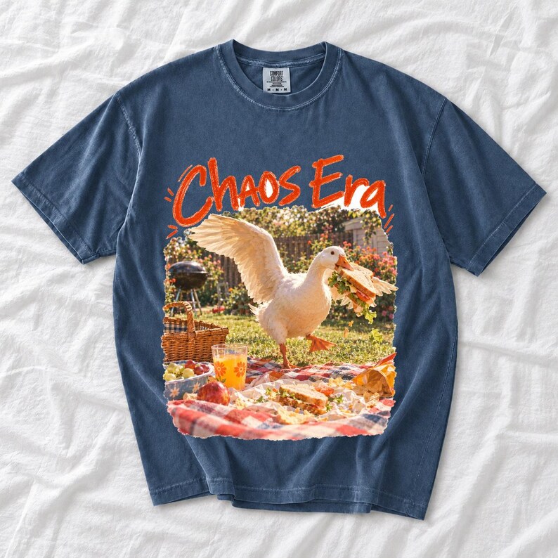 Goose stealing a sandwich from a picnic blanket, 90s film photo style, text "Chaos Era"
