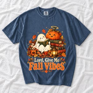 Smiling pumpkin with a halo beside a stack of books and a lantern, text "Lord, Give Me Fall Vibes", retro fall illustration