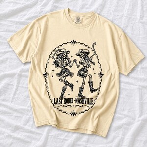 Two cowgirl skeletons in hats line dancing in a starry frame with the text Last Rodeo Nashville