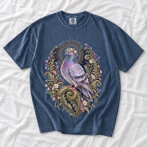 Painted pigeon wearing a daisy crown and glowing halo standing on a fern frond, whimsical cottagecore bird t-shirt art