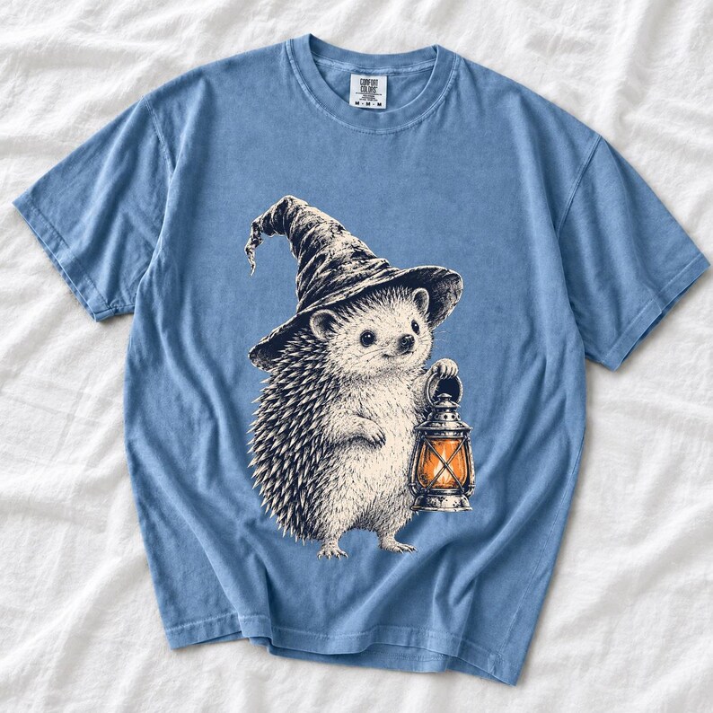 Etched pen illustration of a hedgehog in a witch hat holding a lantern, bone white with orange accent