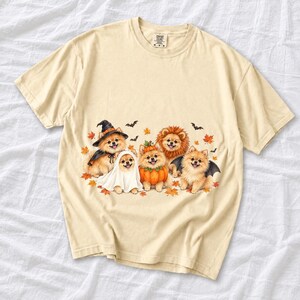Five fluffy watercolor pomeranians in Halloween costumes with autumn leaves and bats