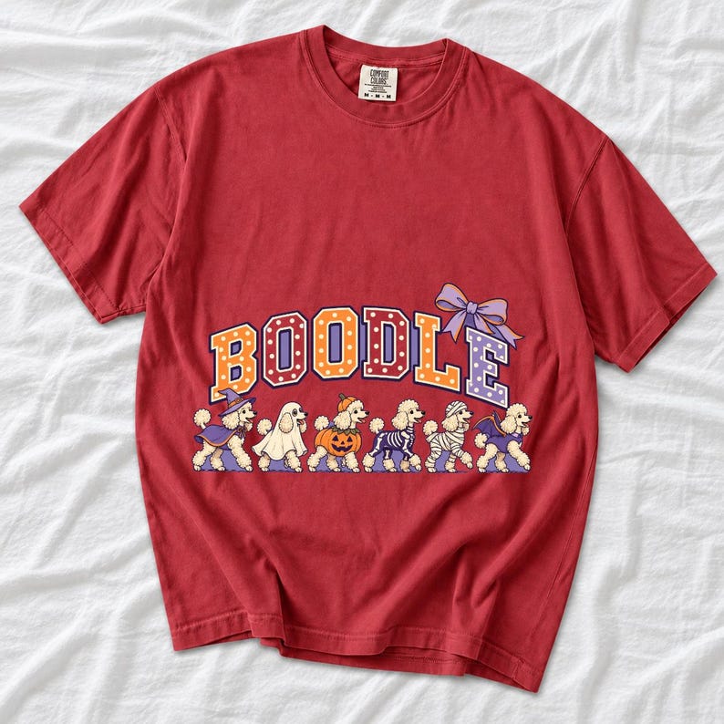 Six poodles in Halloween costumes walking under the arched word BOODLE, lavender and orange polka-dot varsity style
