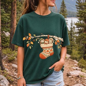 Three watercolor owlets in pajamas and nightcaps tucked into a knitted stocking on a birch branch, one asleep