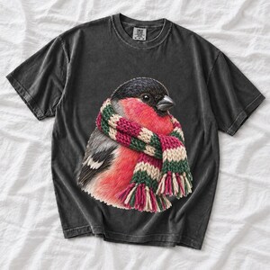 Colored-pencil bullfinch bird wrapped in a chunky striped knit scarf, cozy winter birdwatcher t-shirt art