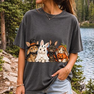 Realistic illustration of four bunnies in witch, ghost, vampire cape and pumpkin costumes in a row