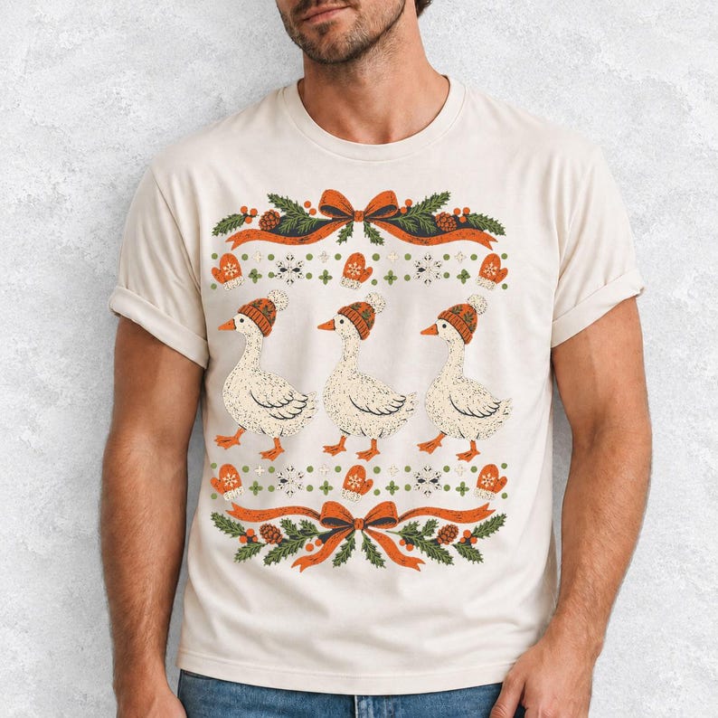 Three geese in pompom knit beanies with mittens, snowflakes and pine borders, retro winter t-shirt graphic