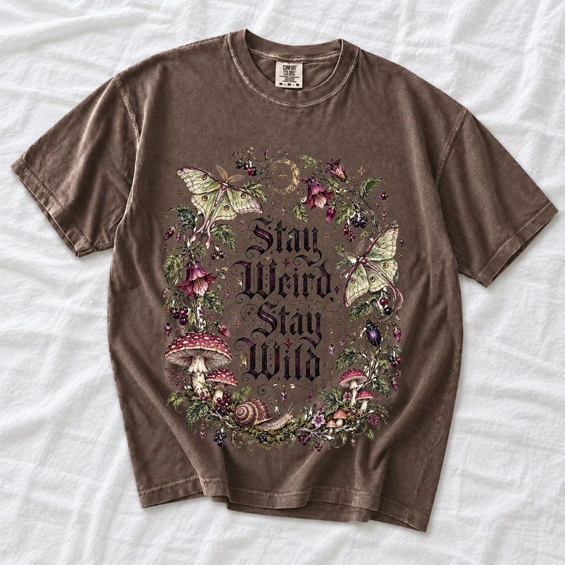 Victorian-style wreath of nightshade, luna moths and toadstools around the words "Stay Weird, Stay Wild"