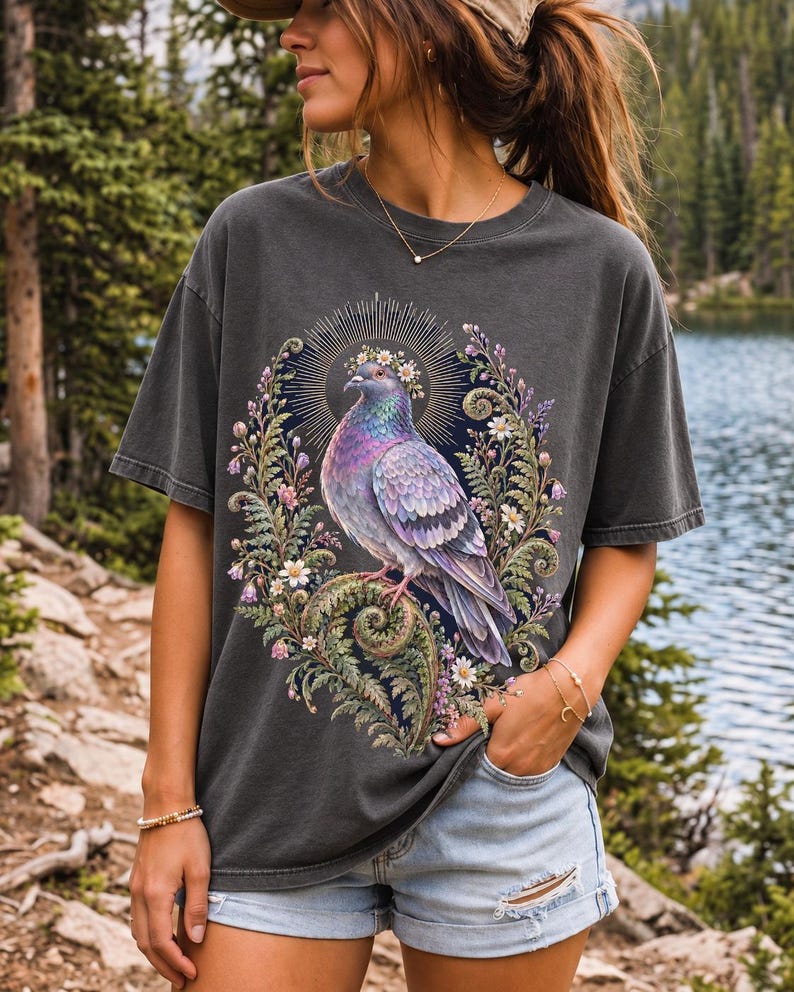 Painted pigeon wearing a daisy crown and glowing halo standing on a fern frond, whimsical cottagecore bird t-shirt art