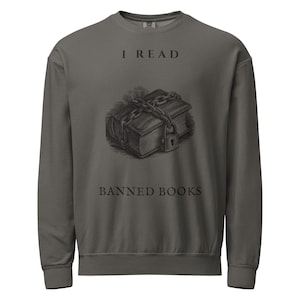 May include: A charcoal grey crewneck sweatshirt featuring a graphic of a book wrapped in chains with a padlock. The text "I READ" is printed above the book illustration, and the text "BANNED BOOKS" is printed below the illustration in black.