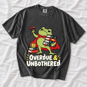 Grumpy cartoon frog librarian holding a stamp and a stack of books with the text Overdue & Unbothered