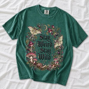 Victorian-style wreath of nightshade, luna moths and toadstools around the words "Stay Weird, Stay Wild"