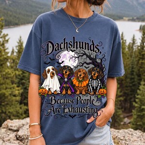 Four dachshunds in Halloween costumes under a spooky tree with text Dachshunds, Because People Are Exhausting