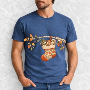 Three watercolor owlets in pajamas and nightcaps tucked into a knitted stocking on a birch branch, one asleep