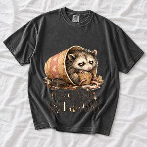 Tired opossum inside a tipped paper coffee cup with the text "I Was Fine Until I Wasn't", sepia watercolor sketch