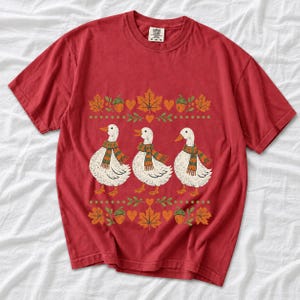 Three white ducks in striped scarves with acorn and maple leaf borders, retro screen print fall t-shirt art
