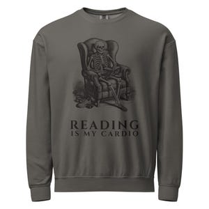May include: A charcoal grey crewneck sweatshirt featuring a black graphic of a skeleton sitting in an armchair reading a book with a pair of trainers on the floor. The text below the graphic reads, "READING IS MY CARDIO" in a serif font.