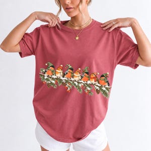 Watercolor bullfinches and robins in elf hats and scarves on a snowy pine branch