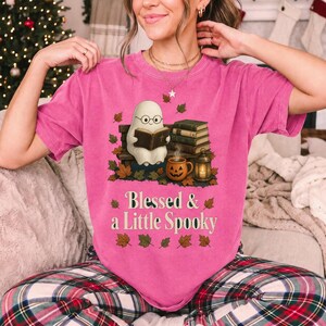 Cute ghost with glasses reading a Bible with a candle and mug, text "Blessed & a Little Spooky", retro fall illustration