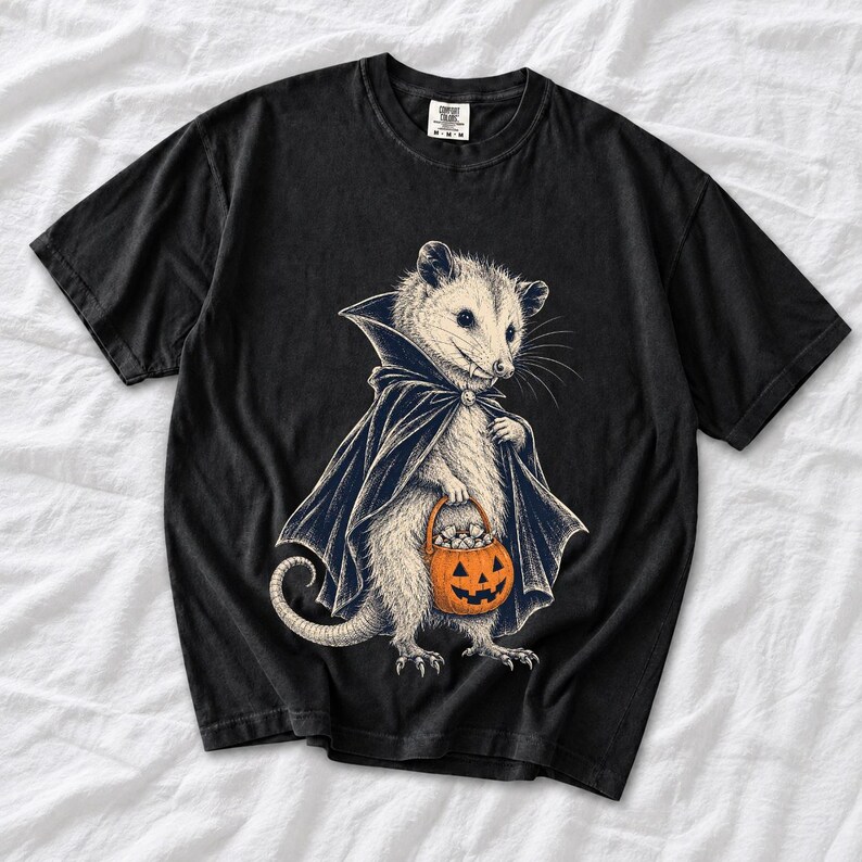 Etched pen illustration of an opossum in a vampire cape holding a candy pumpkin, bone white with orange accent