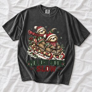 Two sloths in ugly sweaters riding a sled with lights and the text Holiday Mode: Slow