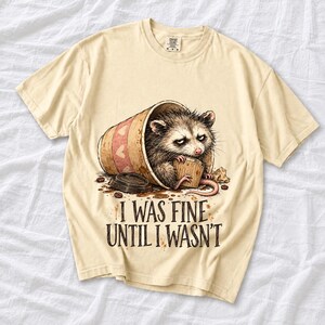Tired opossum inside a tipped paper coffee cup with the text "I Was Fine Until I Wasn't", sepia watercolor sketch