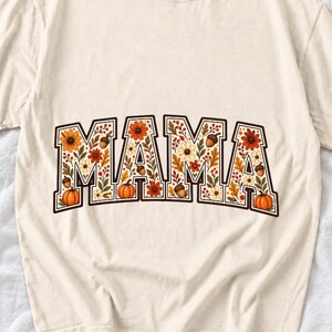 Arched varsity word MAMA filled with fall flowers and acorns in cream, rust and mustard