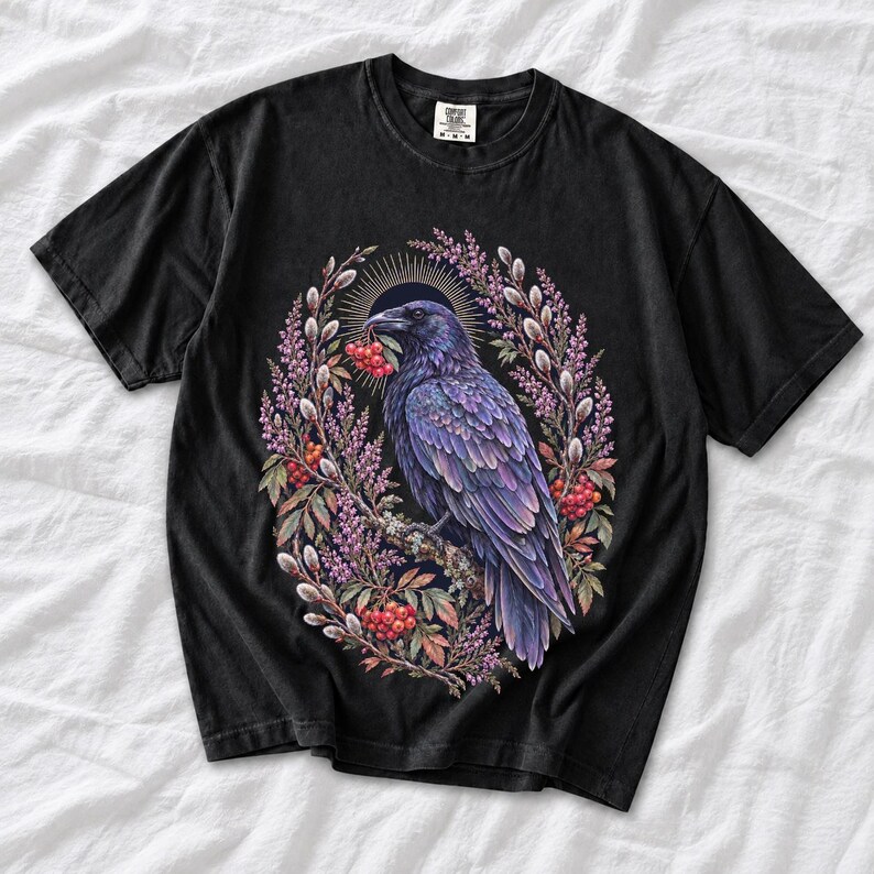 Raven holding a rowan berry inside an oval wreath of heather and catkins, painted cottagecore bird illustration
