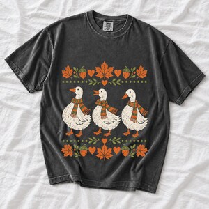 Three white ducks in striped scarves with acorn and maple leaf borders, retro screen print fall t-shirt art