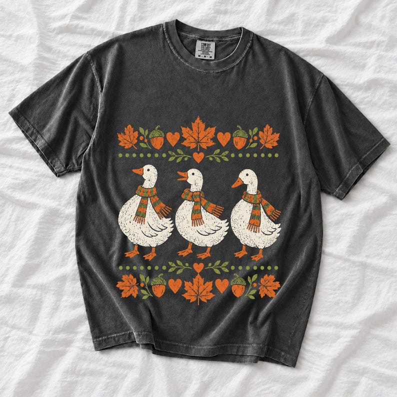 Three white ducks in striped scarves with acorn and maple leaf borders, retro screen print fall t-shirt art