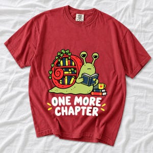 Cartoon snail reading a book with a bookshelf shell and the text One More Chapter