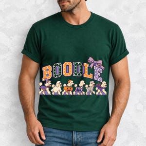 Six poodles in Halloween costumes walking under the arched word BOODLE, lavender and orange polka-dot varsity style